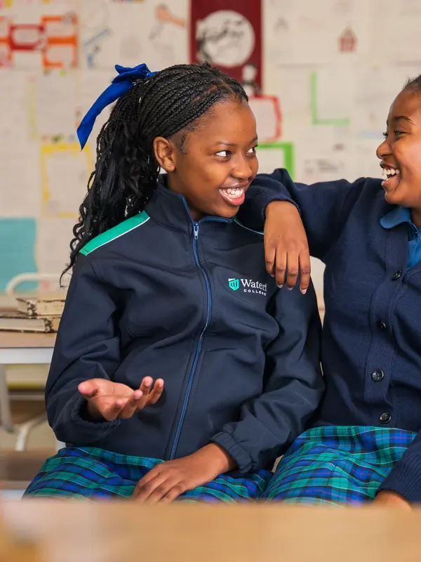 Two students laughing together with an arm around a shoulder