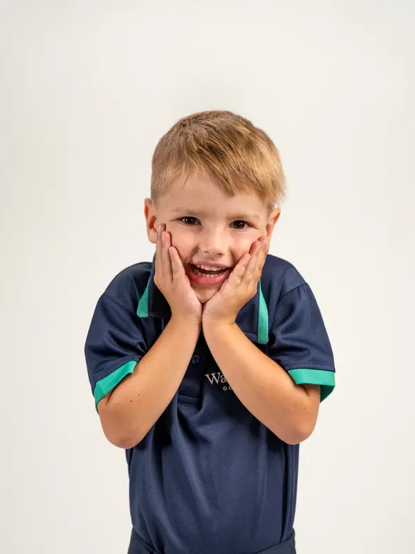 A young child with their hands on their cheeks, laughing