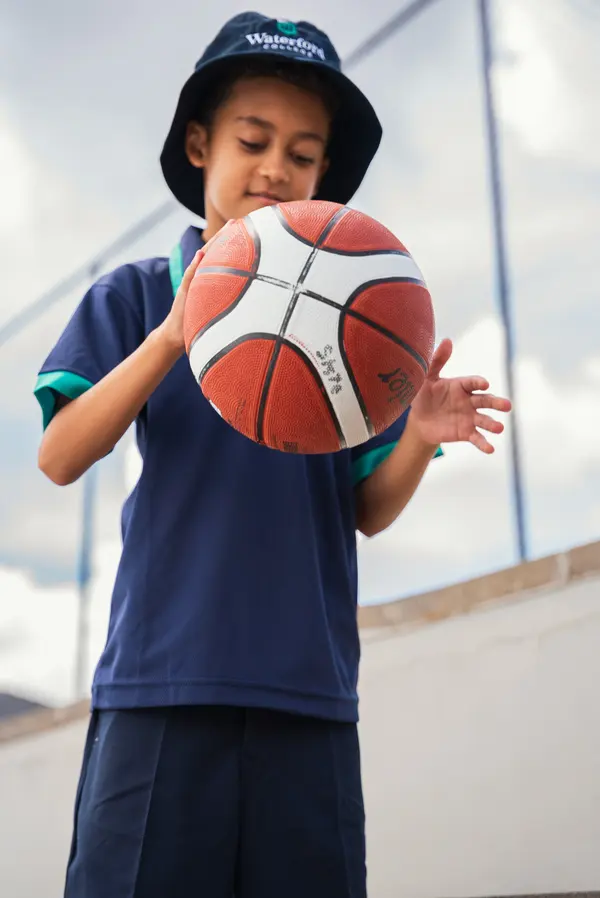 A student holding a basketball above their head