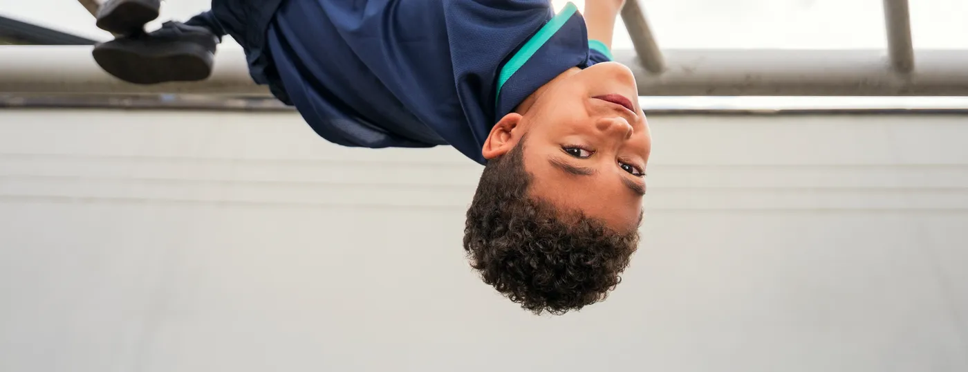 A child hanging upside down from the climbing bars, laughing