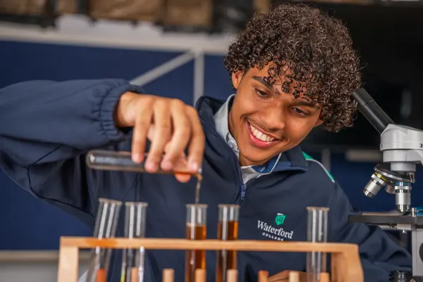 A student working with test tubes and a microscope