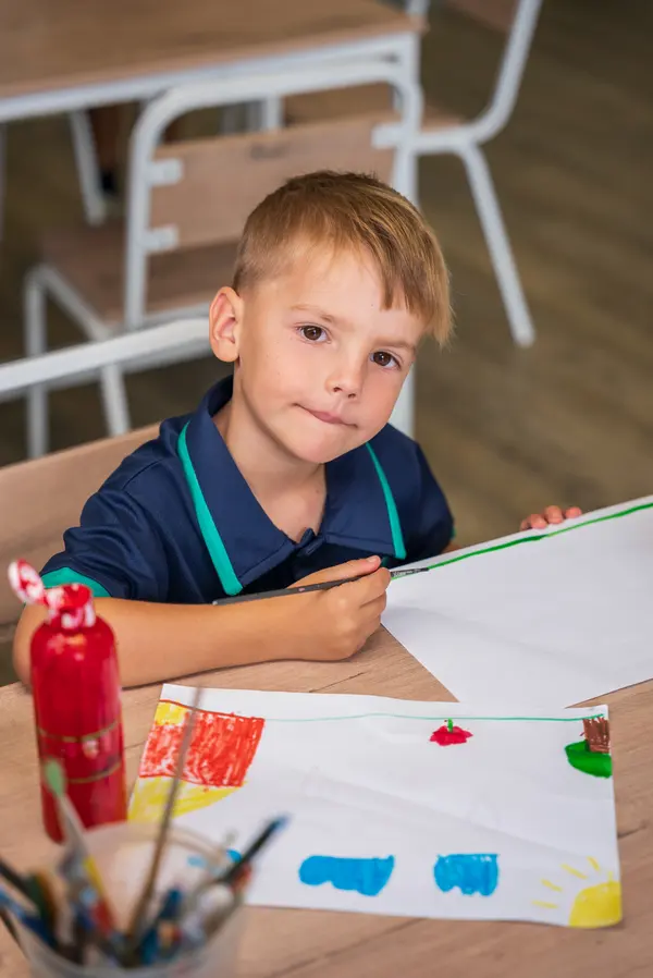 A child writing at a classroom desk