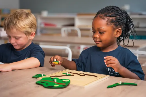Two young children working with a wooden puzzle