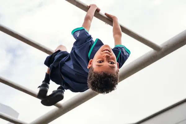 A child hanging upside down from monkey bars